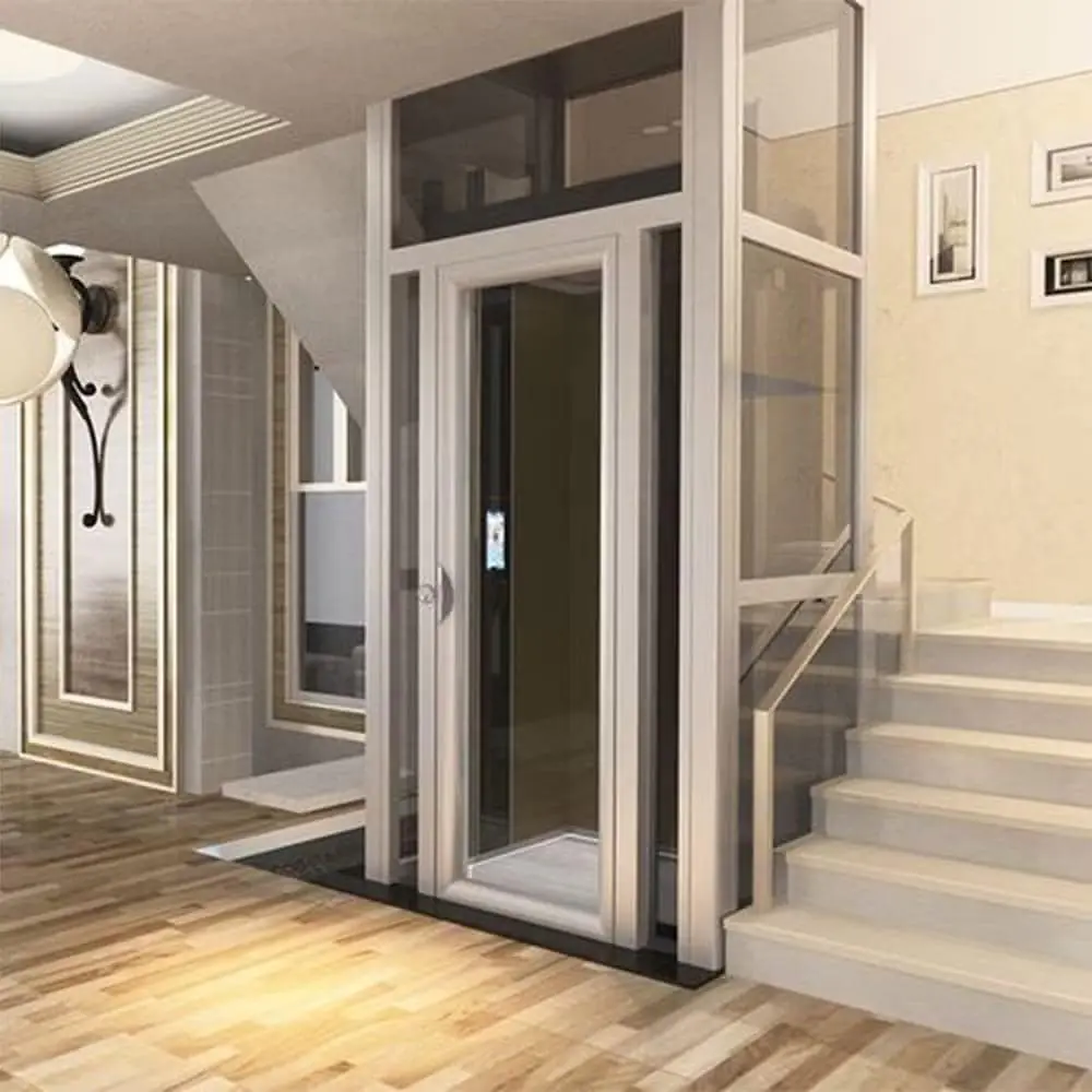 A glass and aluminium frame CASTOR home lift shaft installed beside a staircase in a residential foyer with wood flooring.