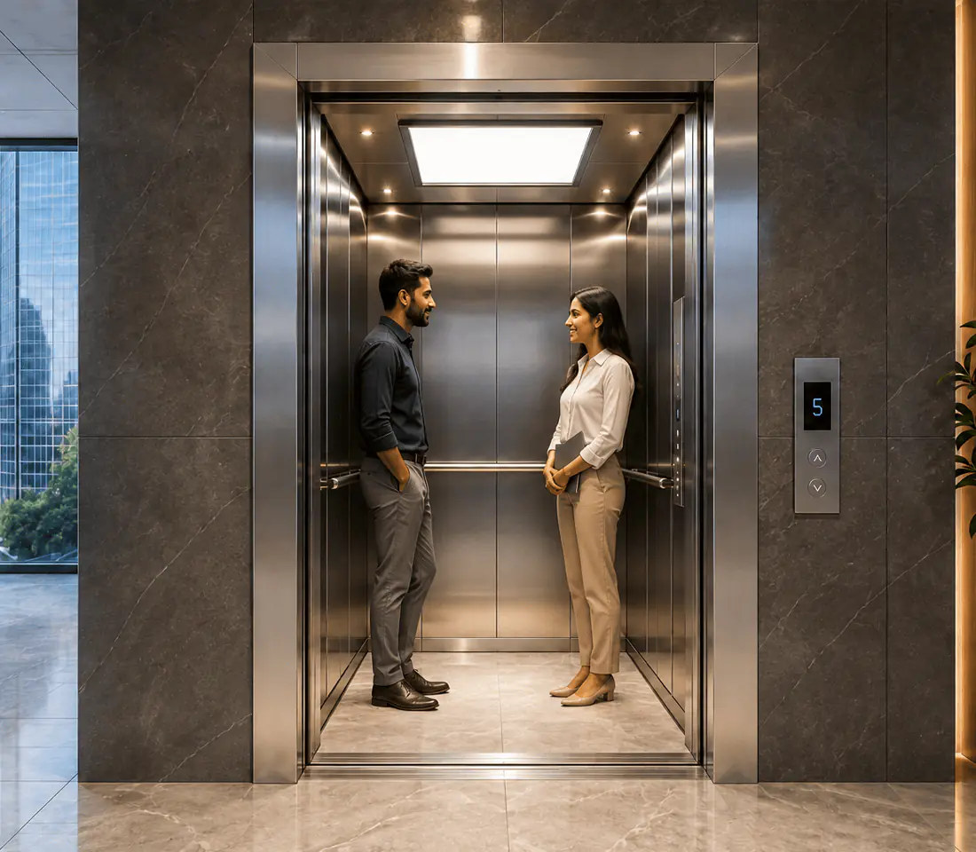 Row of polished stainless steel elevator doors along a lobby corridor leading to a reception and security turnstile area.