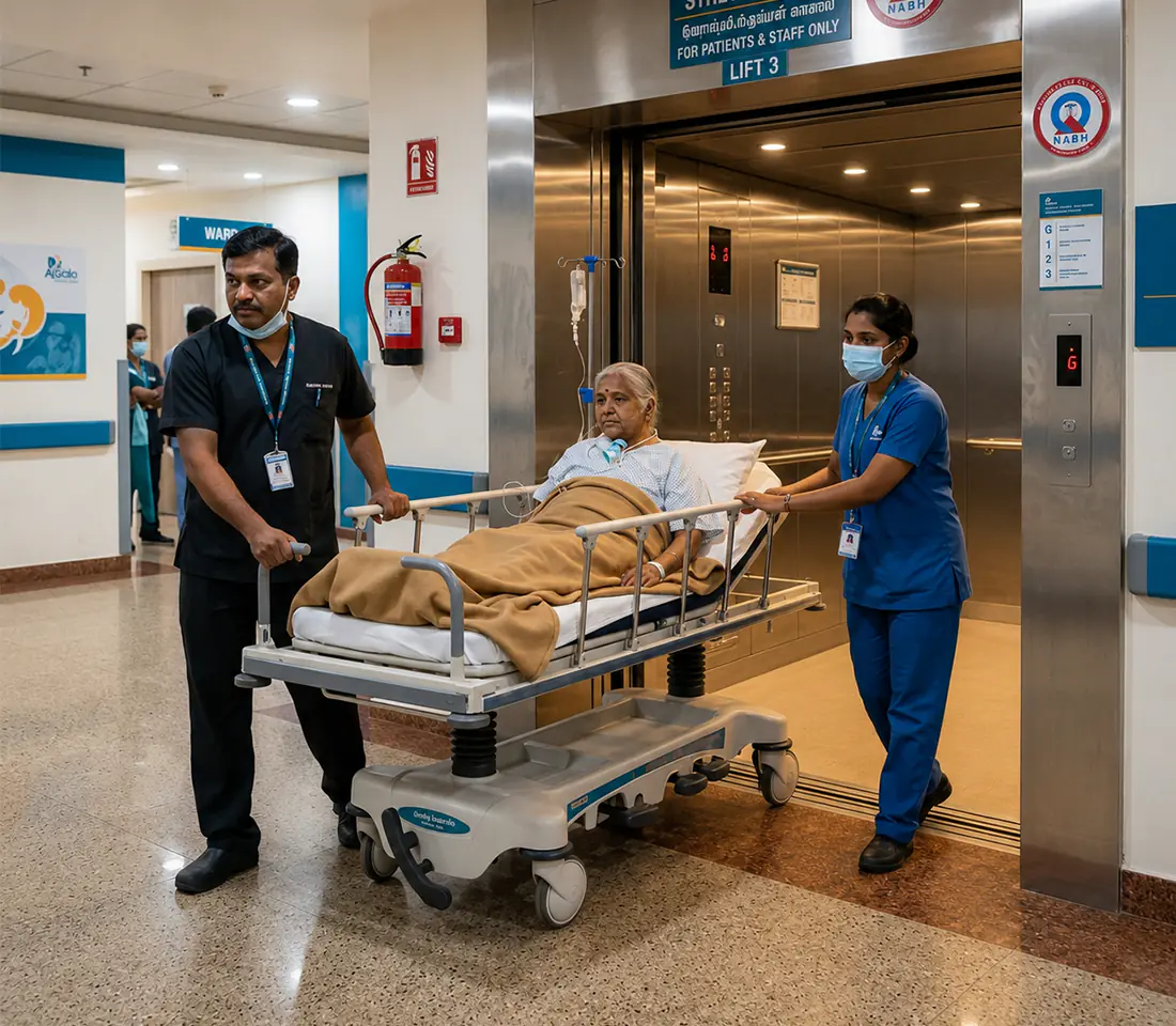 Empty stretcher lift cabin with white panelled walls, dual handrails, and stainless steel doors open onto a hospital corridor.